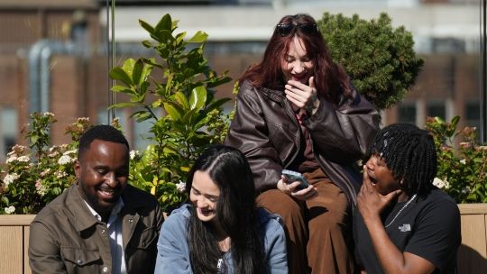 group of students looking at their phones at the roof garden