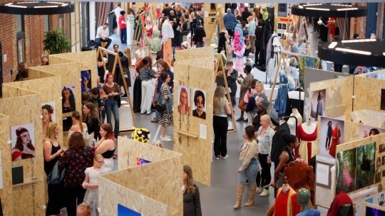 Visitors viewing students’ artwork displayed on wooden panels at the Art and Design Summer Show 2025 in the Brunel Engine Shed