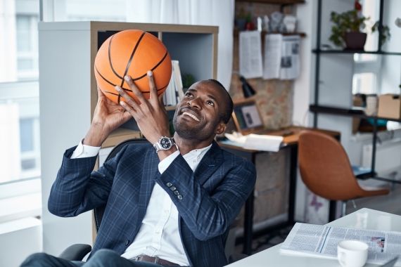 Male at desktop holding basketball ball