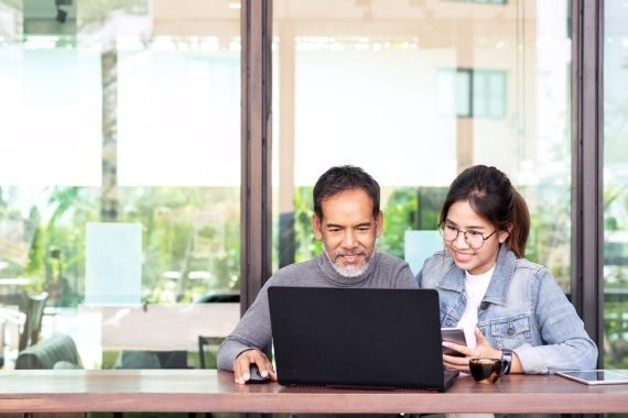 Asian man and young adult sitting at laptop together