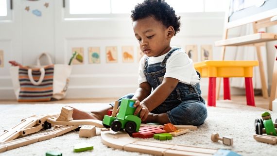 Black child playing with train set on floor 