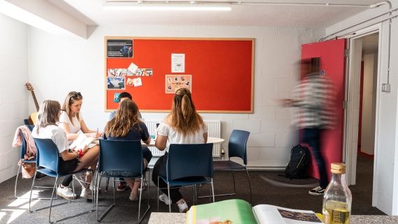 four students working together at a round table in a communal area