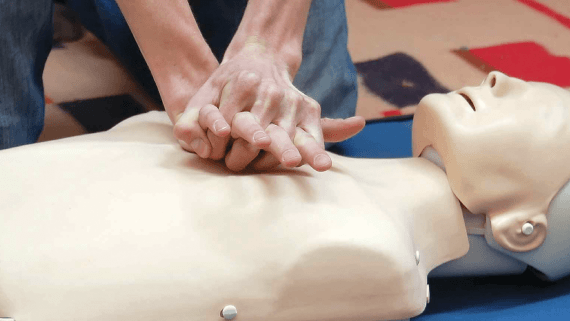A BNU student with his hands on a dummies chest, learning to give CPR.