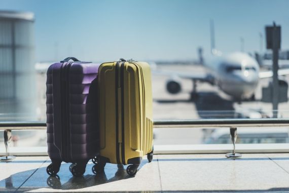 two suitcases in an airport with plane in the background