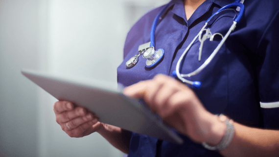 A Nurse looking on a tablet dressed in their uniform