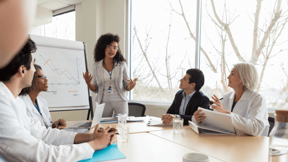 Business meeting amongst five members of staff sat around a table