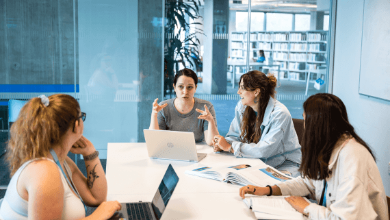 Three BNU students in a meeting with a member of staff sat around a table in the BNU library