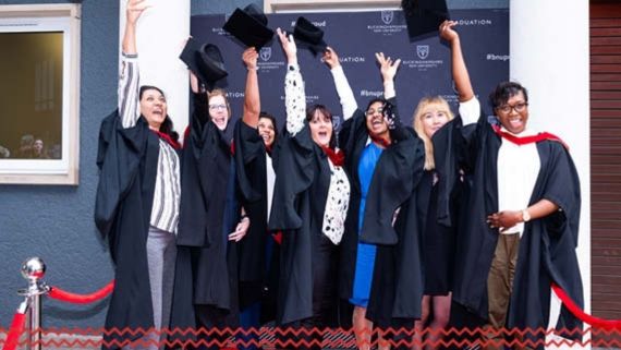 Seven students throwing their mortarboards in their air on graduation day