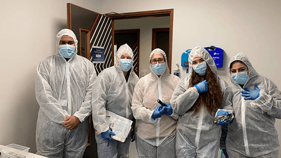 A group of 5 Criminology students in forensic uniform stood in a line facing the camera