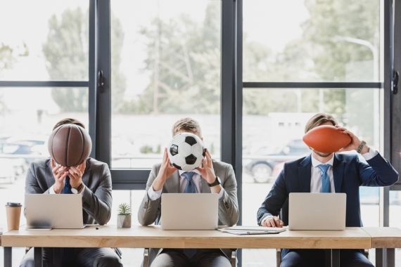 three people holding sports balls against their faces in an office