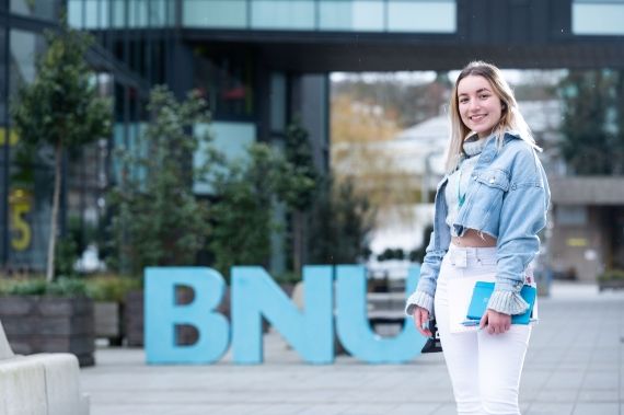 Female student outside BNU sign at High Wycombe campus