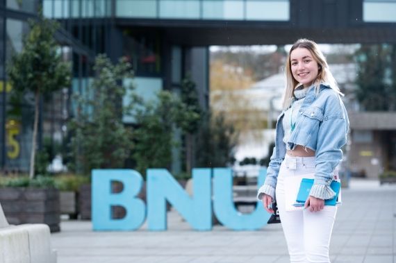 Female student outside BNU sign at High Wycombe campus