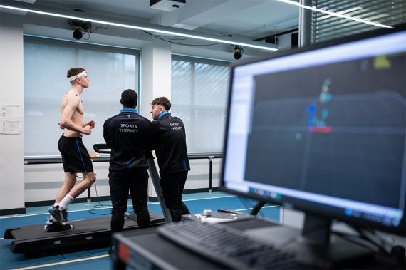 A student on a treadmill whilst two Sports Therapy students monitor his heart rate