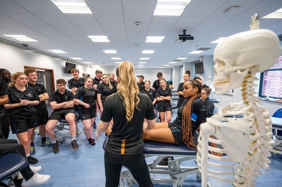 A Sports Therapy student lying down as a demonstration is given to the rest of the class.