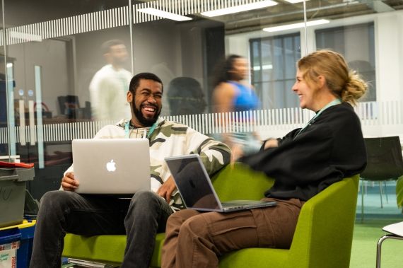 Two students with laptops in a classroom