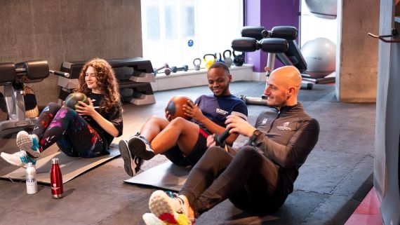 BNU lecturer and 2 students exercising with medicine balls on yoga mats in a gym space