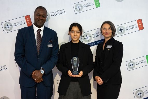 Graduate Associate Shelley Jones posing with trophy for Security Institute Academic Achiever Award alongside two attendees at the Security Institute’s Annual Conference
