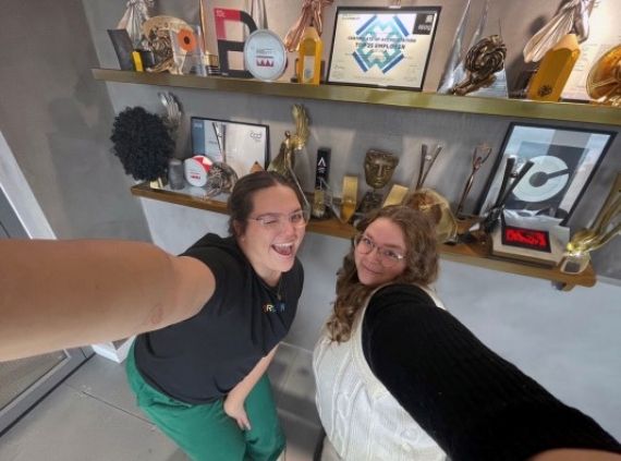 Anna Belka and Eve Nadin Creative Advertising students stood next to all their trophies lined up on the wall.