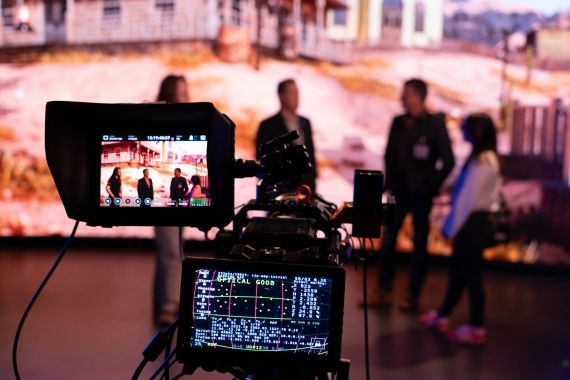 Four people talking in front of an LED Screen, cameras pointing at them