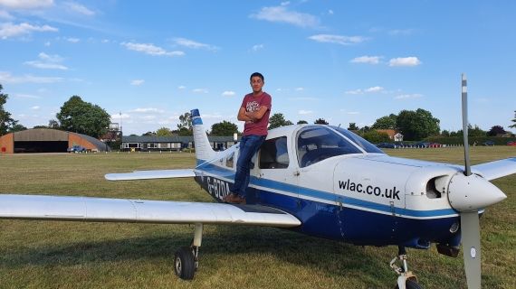 Student Jacob standing on the wing of a plane at airfield