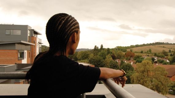 Bucks student standing on balcony of student halls looking over fields
