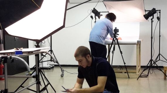 Two people setting up camera equipment in a photography studio