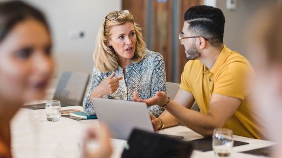 Female lecture with male student talking about  work at desk 