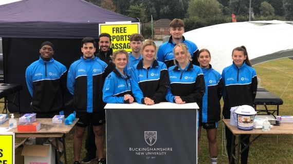 10 students in BNU uniform smile for photo at Stoke Mandeville Stadium
