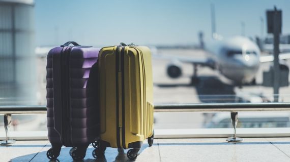 two suitcases in an airport with plane in the background