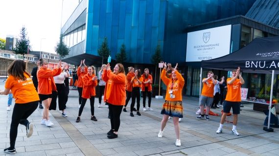 group of freshers helpers dancing outside the gateway building