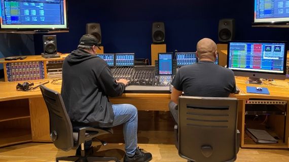 Two people facing away from camera using Dolby studio equipment