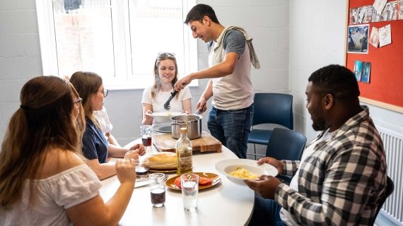 5 students sitting around a table in a Brook Street kitchen eating dinner
