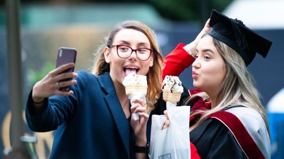 Female graduand taking a selfie with friend