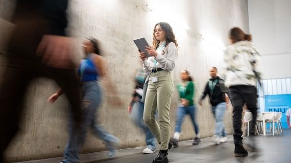 Students walking past concrete wall in gateway
