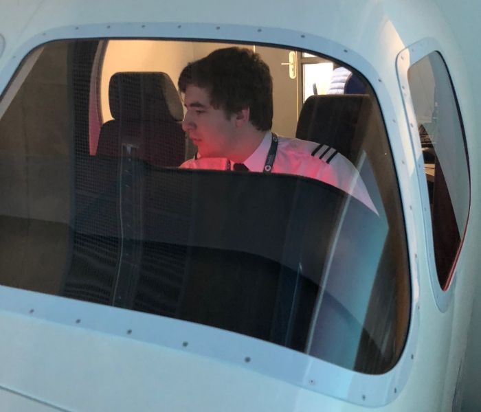 a student in the flight simulator with cameraman on the outside 