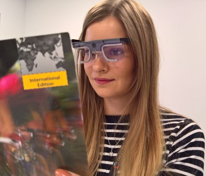 Female student wearing eye tracker while reading a magazine