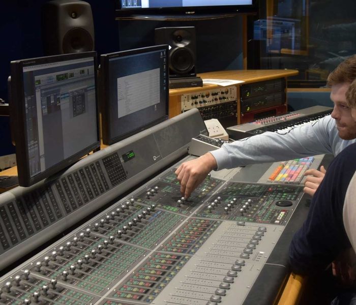 two male students in the music studio turning the control buttons
