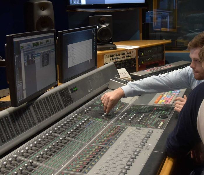 two male students in the music studio turning the control buttons