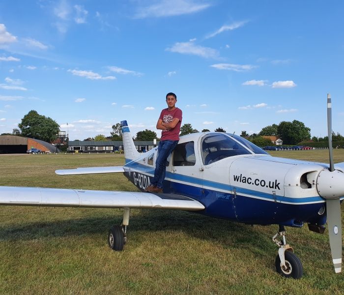 Student Jacob standing on the wing of a plane at airfield