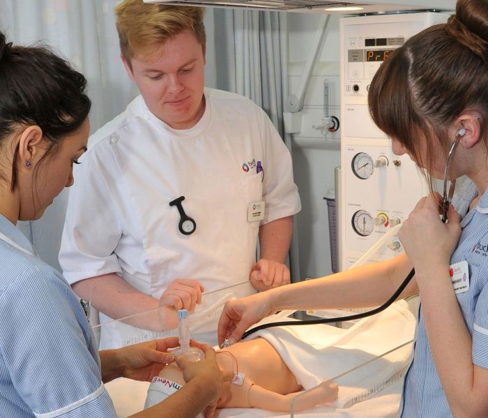 Three Bucks student nurses using a stethoscope on a child mannequin