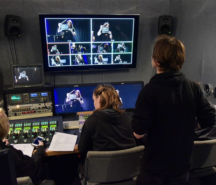 Three students in a tv studio looking at the tv screen