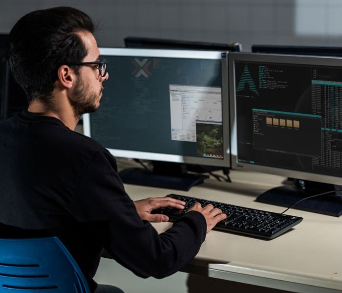 Man with glasses using linux software on computer at desk
