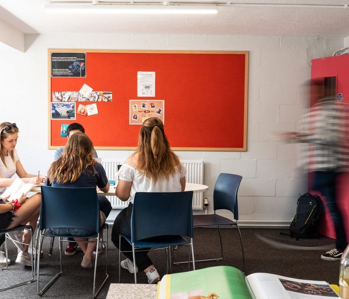 four students working together at a round table in a communal area