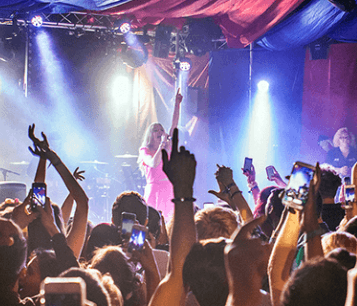 A Bucks Students' Union event held in a music concert with students waving their arms in the air whilst looking towards the stage