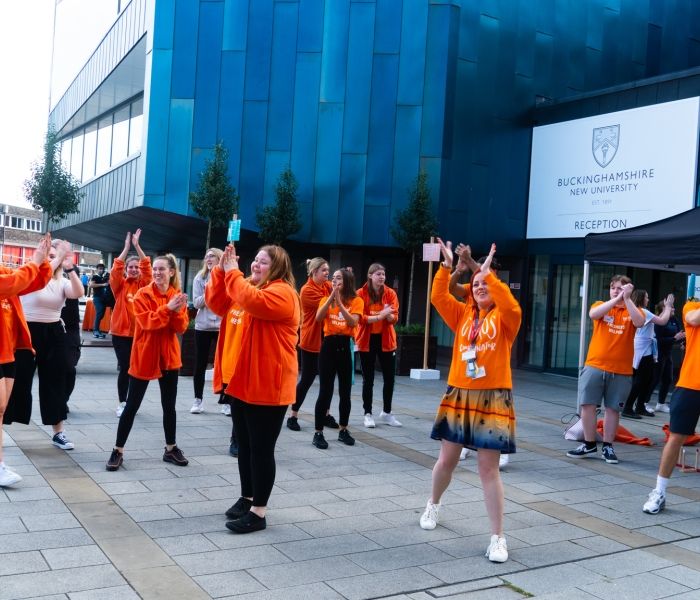 group of freshers helpers dancing outside the gateway building