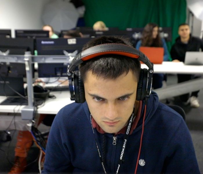 Male student wearing headphones while working at BNU based at Pinewood Studios