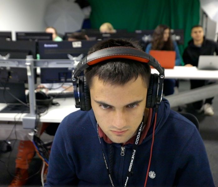 Male student wearing headphones while working at BNU based at Pinewood Studios