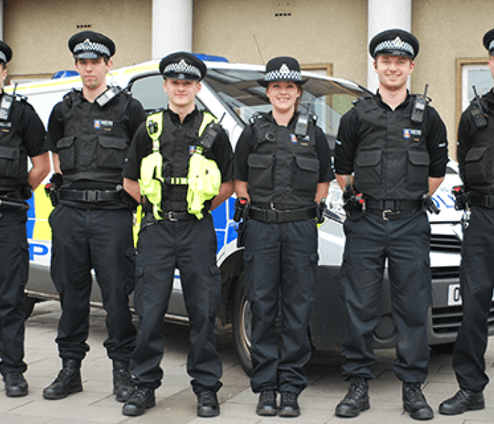 Five BNU policing students in uniform stood in a line in front of a Police van near the Gateway reception on the High Wycombe campus.