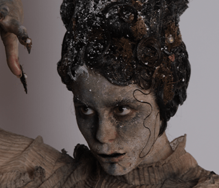 A BNU Hair and Make-up student with an ash-effect face paint applied whilst holding their right hand up in the air.