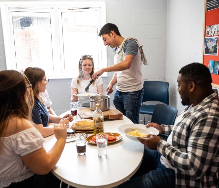 5 students sitting around a table in a Brook Street kitchen eating dinner